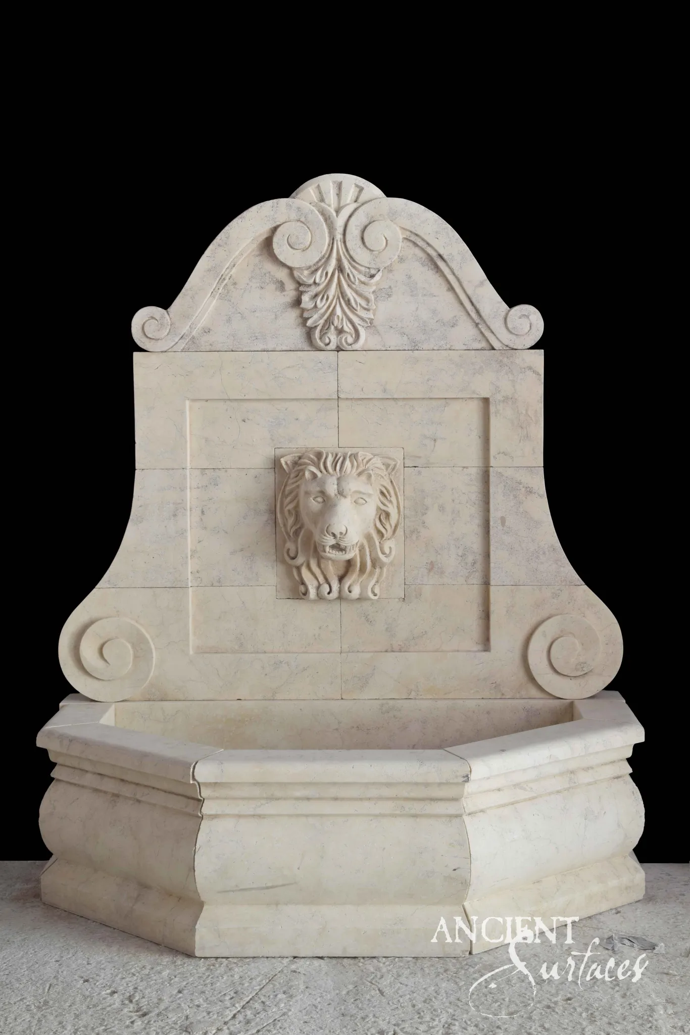 Hand-carved antique limestone wall fountain with a lion's-head spout and scrolled cresting